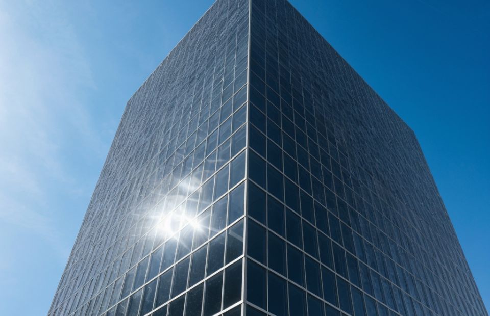 A glass-windowed, large office building in front of clear blue skies