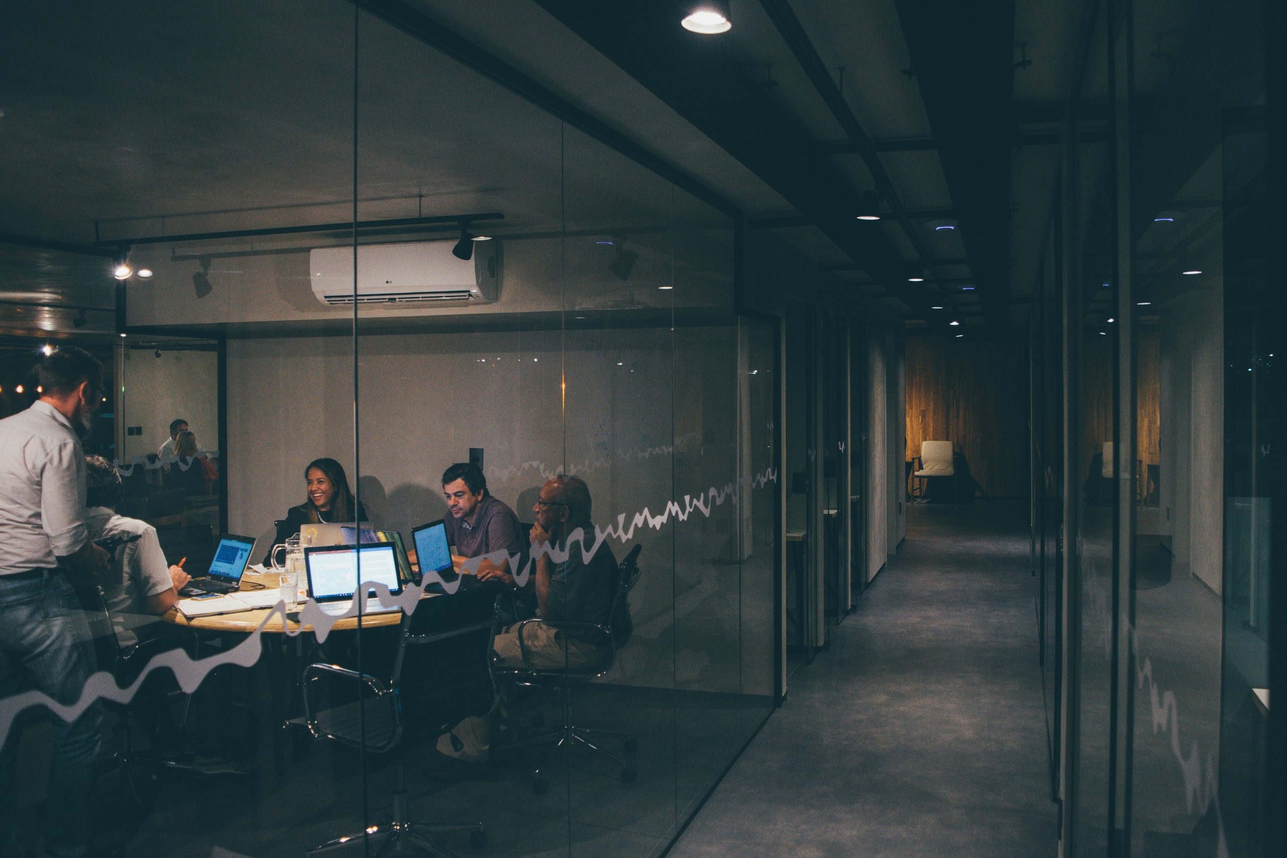 A group of people sitting around a table working on laptops